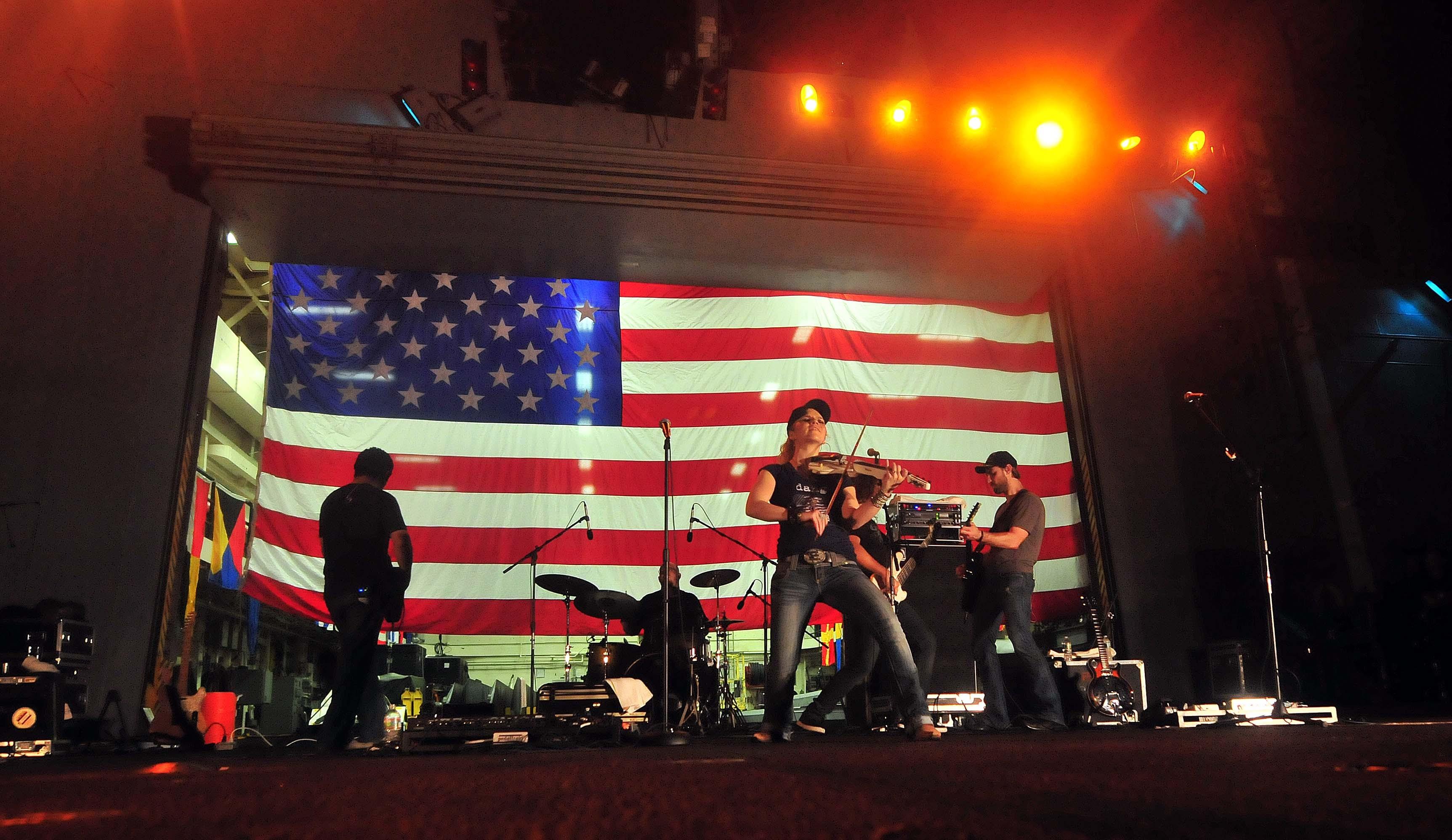 Musician playing on stage in front of flag